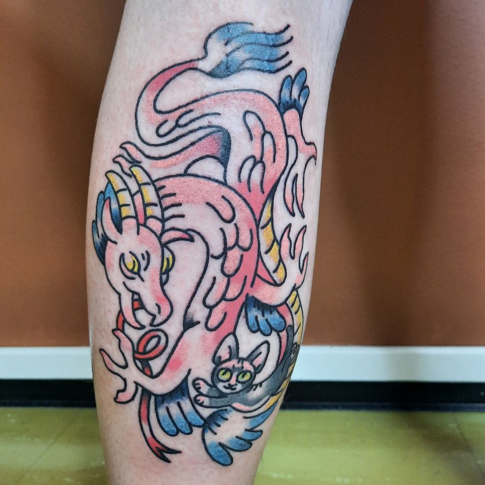 Photo of pink dragon and cat tattoo done on back of the leg.