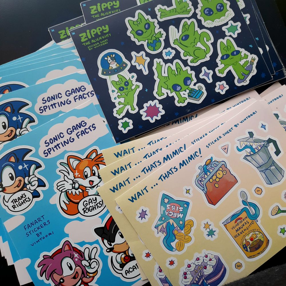 Photo of three different sticker sheet designs. One is Sonic themed named 'Sonic gang spitting facts', second is alien cat themed named 'Zippy the alien kitty' and third is mimic themed called 'Wait... That's mimic!'. 