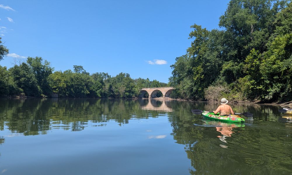 Lady in a green kayak heading towards a bridge