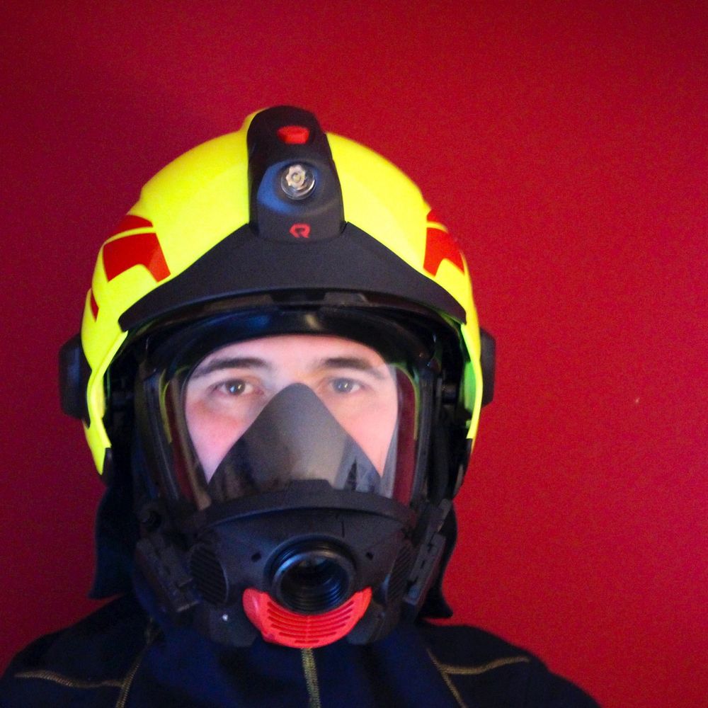 Me with a yellow firefighter helmet and a SCBA Mask. 
The picture has a red background. 