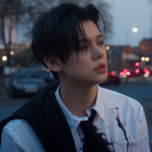 Blurry Ghost Girl YJ. The sky is darkening, his black hair is falling into his face. The eye makeup is smokey 😶😶😶