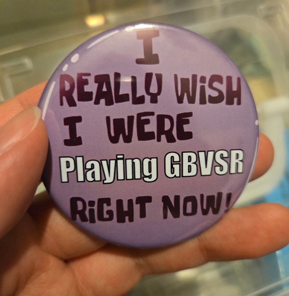 Picture of a can badge i made using a machine i bought. Its says "I really wish I were playing gbvsr right now" in the same style as the button worn by squidward in spongebob 
