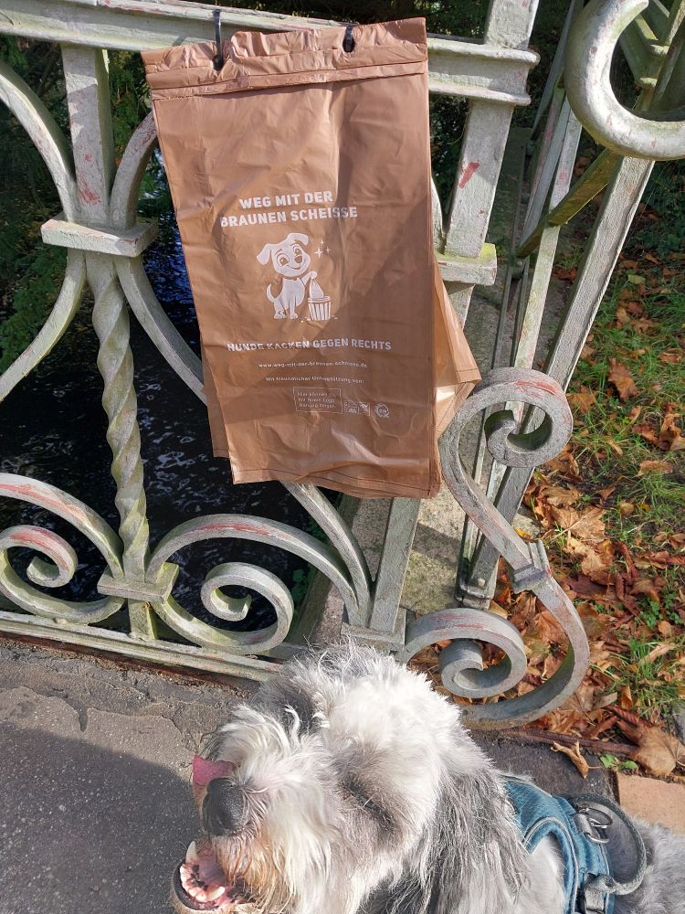 Hund vor Kackbeuteln mit der Aufschrift: "Weg mit der braunen Scheisse"
