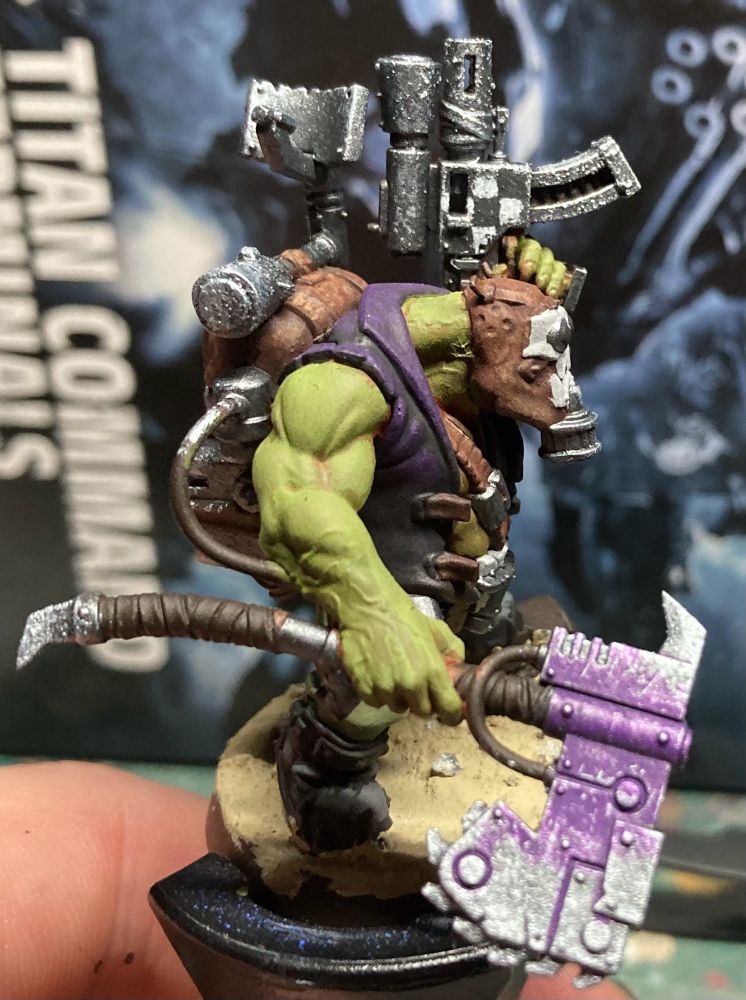Same alt text for both:
Image of warhammer 40k ork with heavily weathered panels on weapons. The axe showing some purple still and the pistol showing a black and white chequer pattern. 