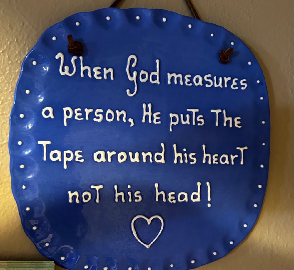 A sign that says “When God measures a person, He puts the tape around his heart not his head!” 