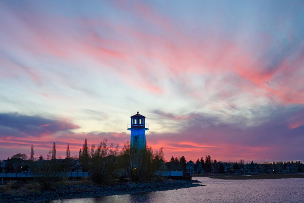 A lighthouse at the lake marina with red clouds in the distance