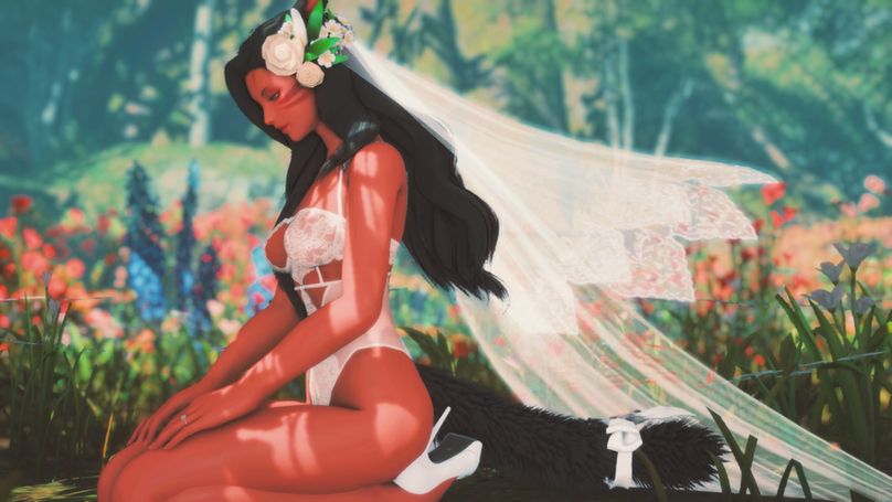 Annette in bridal lingerie, resting on her knees in a field of flowers with her veil billowing behind her