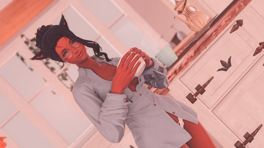 Annette, in an oversized and unbuttoned shirt, smiles at the viewer while holding a mug.