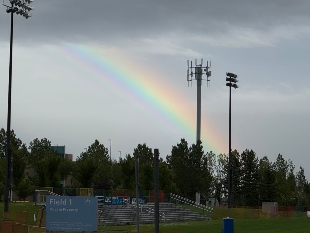 Supernumerary rainbow over Mount Royal University in Calgary. A bright and wide rainbow with with a green hue beneath the violet layer.