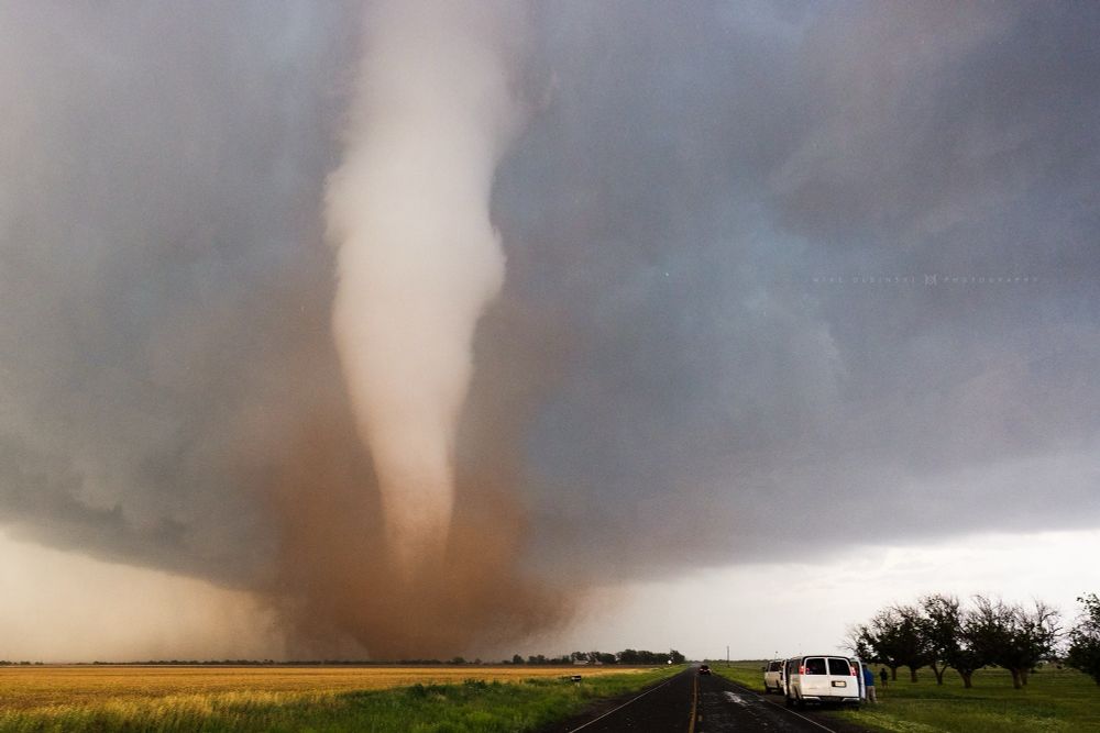 White tornado down the middle of the road with brown dirt being spun up