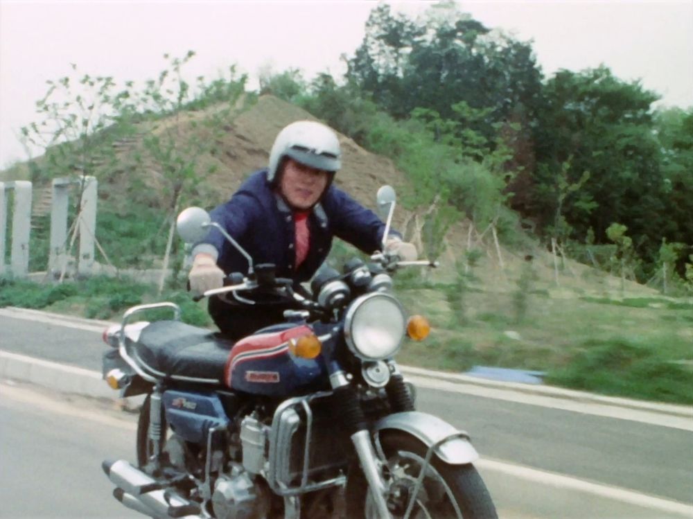 Now he's sitting on the edge of the seat with his feet resting on the exhaust pipes