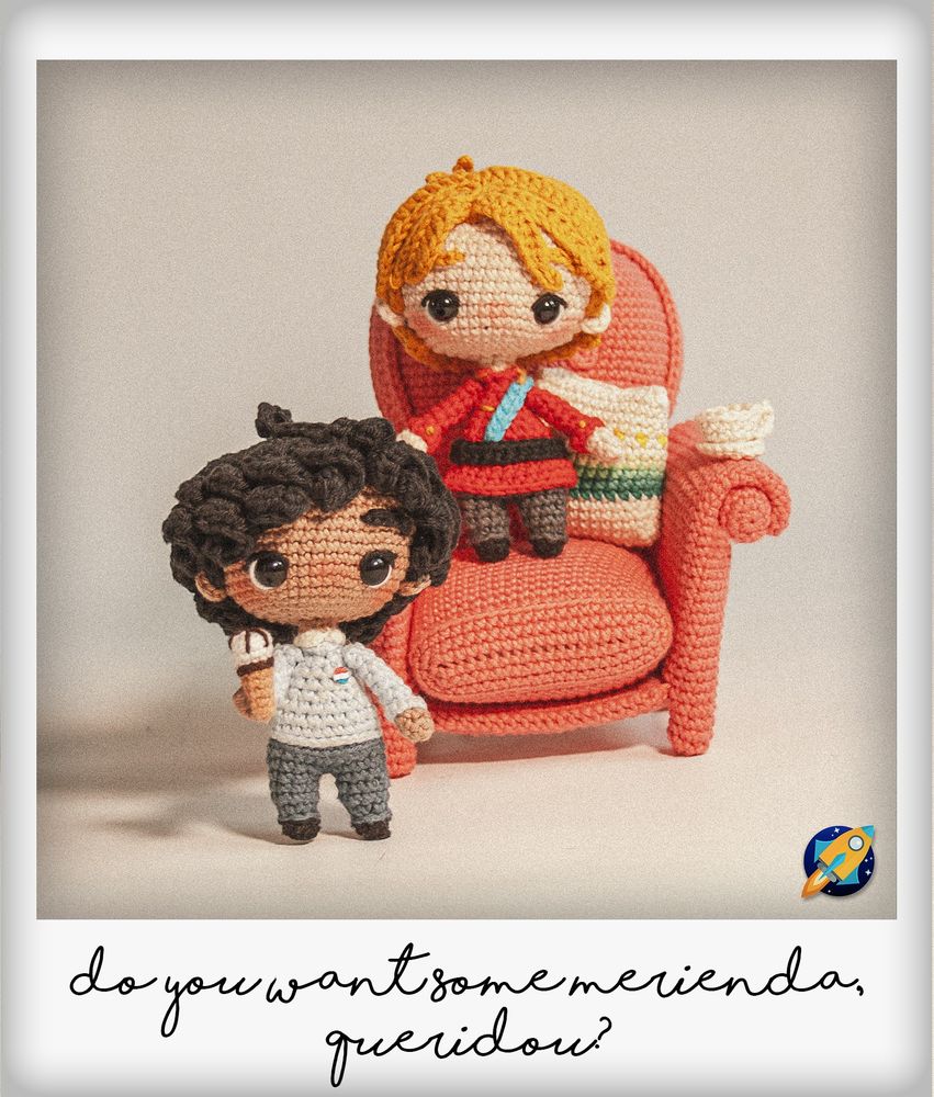 Foto simulando una polaroid de dos amigurumis de estilo chibi de Alex y Henry, los protagonistas de "Rojo, Blanco y Sangre Azul", de Casey McQuiston. Alex está de pie a la izquierda, con un helado en la mano, vestido con un jersey azul pastel. Henry está sobre un sillón (también hecho a crochet), vestido con el uniforme de gala de la realeza. Encima del brazo del sillón, hay una tacita sobre su plato.
En los márgenes blancos de la foto está escrito el texto "do you want some merienda, queridou?"