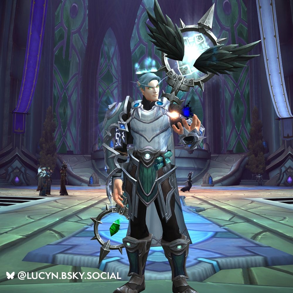 In the center of the image, there is an Elf Priest with silver hair, equipped with silver metal armor. In their open-palmed left hand, there are two spheres swirling around, one made of light and the other of darkness. The elf has a very large metal staff equipped on the back that sprouts two black wings from the top. In between the two black wings, there is a glowing sphere of light, right in the center. Behind the elf, there is a cathedral setting. Below is a large blue and purple rug, and the rest of the ground is covered in stone tiles. In the distance, three very large glass windows cover multiple stories as they go upwards from the ground.