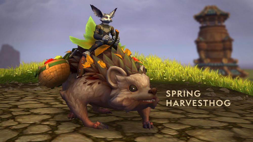 An image of a vulpera player character riding the labeled Spring Harvesthog mount somewhere in the Ohn’ahran Plains. The giant, adorable rodent has brown fur and big brown eyes, with round ears, and thick olive-green quills along its back. The vulpera sits on a saddle made from a large green leaf, with baskets of fruit hanging from each side. Green grass and a blurry view of a centaur tower fill the background beneath a gray sky.