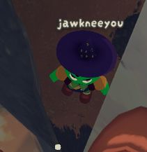 A small green man in a wizard hat looks up, giving a dirty look, in the game PEAK.