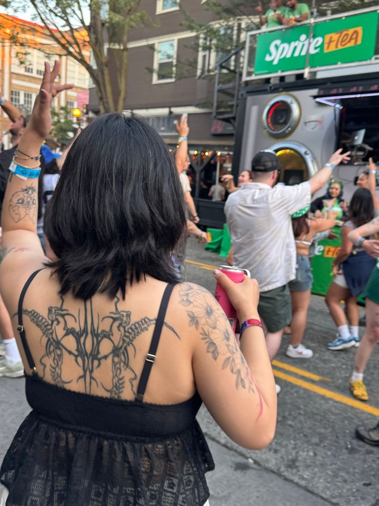 My partner dancing in front of a Sprite promotional stand featuring a DJ playing out the window.