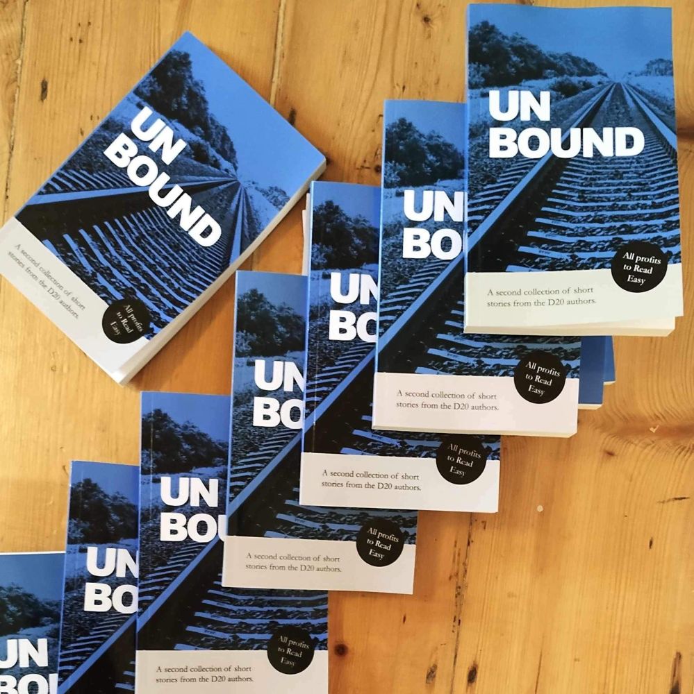 Copies of unbound anthology organised in a staircase pattern. The cover is dark blue with the image of retreating train tracks.