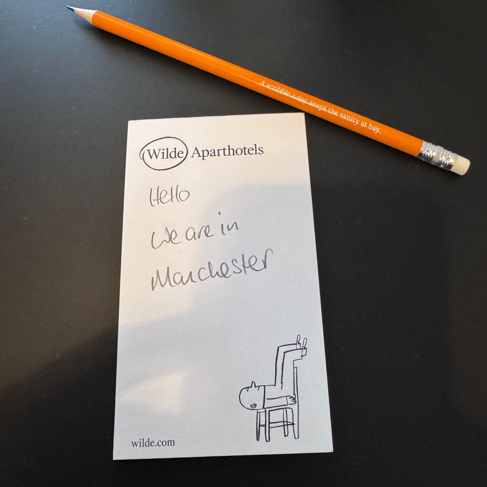 A notepad on which I have written, “Hello. We are in Manchester.”