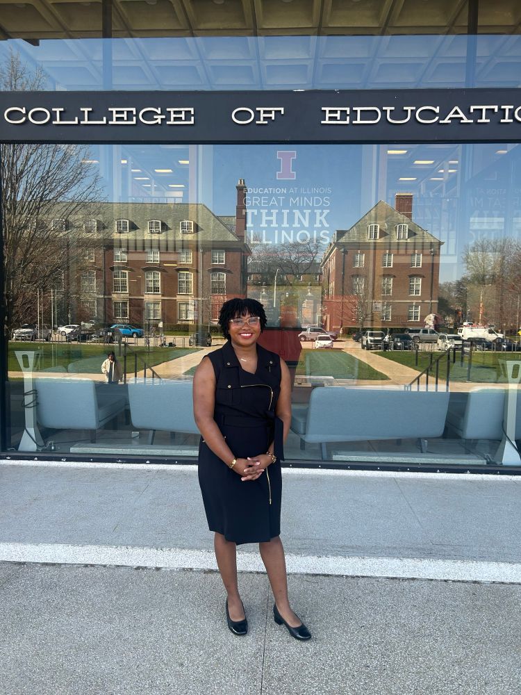 Dr.Destiny in a black dress standing in front of a building
