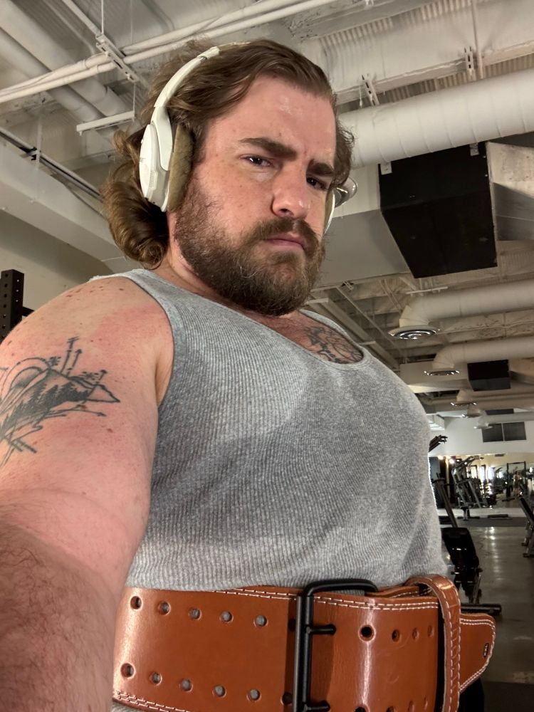 Sweaty guy wearing grey tank and weight lifting belt 