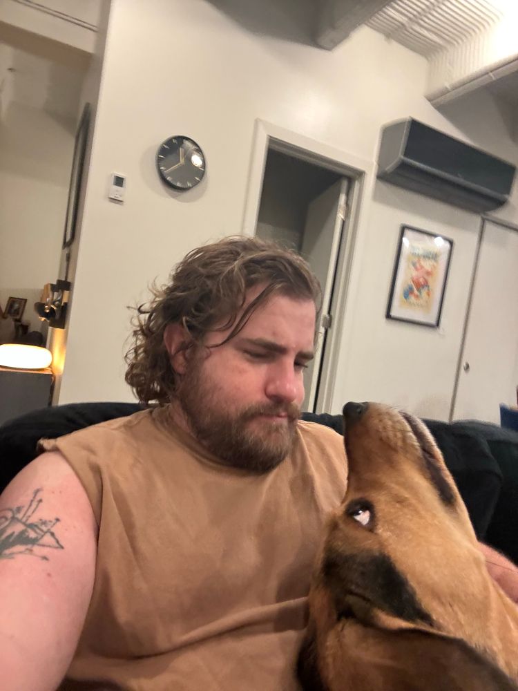 Hound dog doing an upside down snout boop to hairy man 