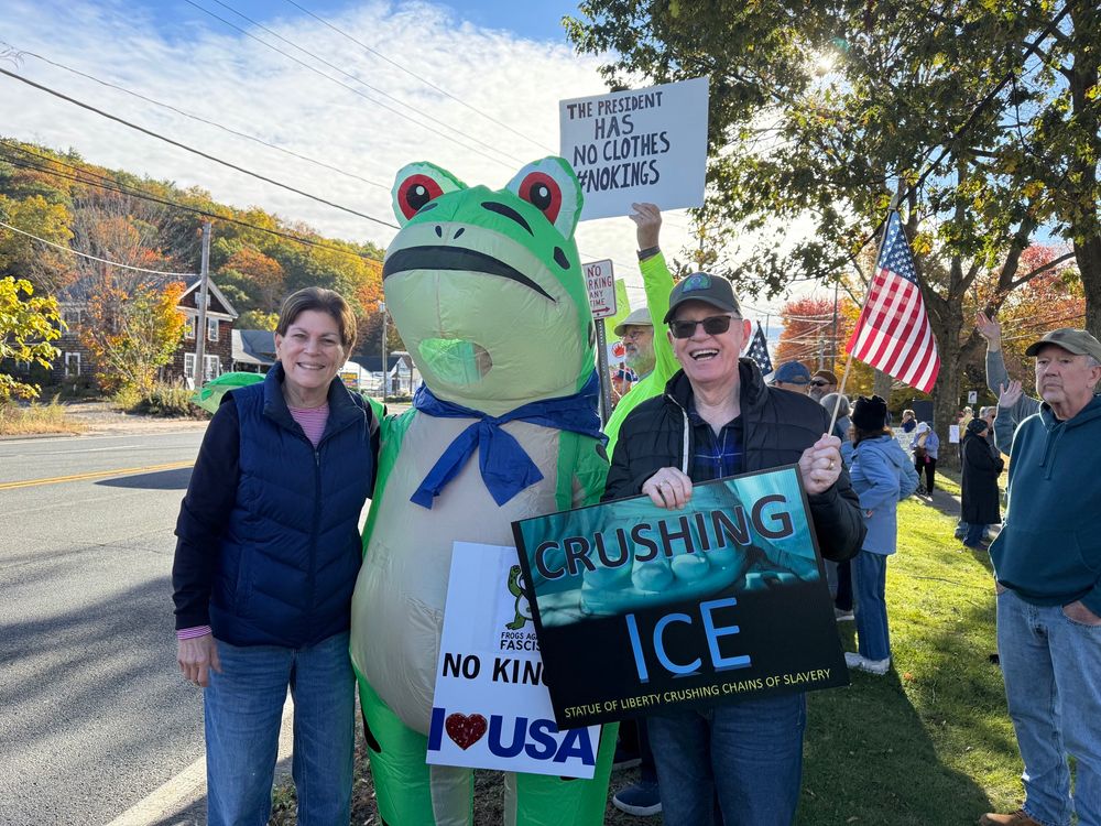 Grandma and Grandpa out protesting. Blow up Frog between them.  Grandpa holding “Flushing Ice” Sign
