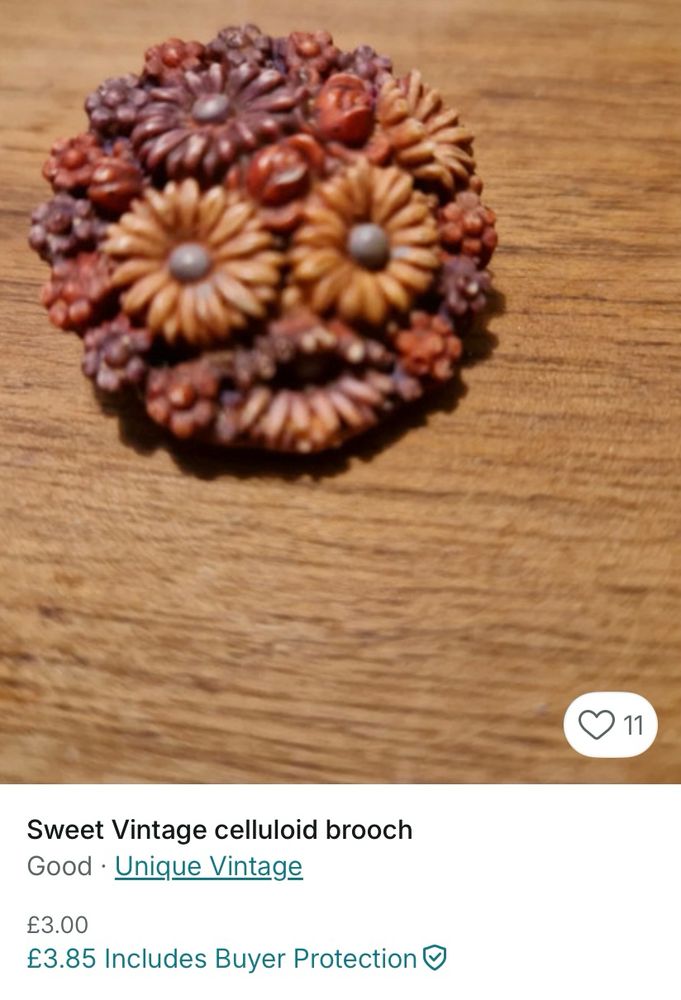 Vintage celluloid brooch in reds, browns and yellows, with the two large yellow flowers appearing to form eyes, and an indentation below making a mouth