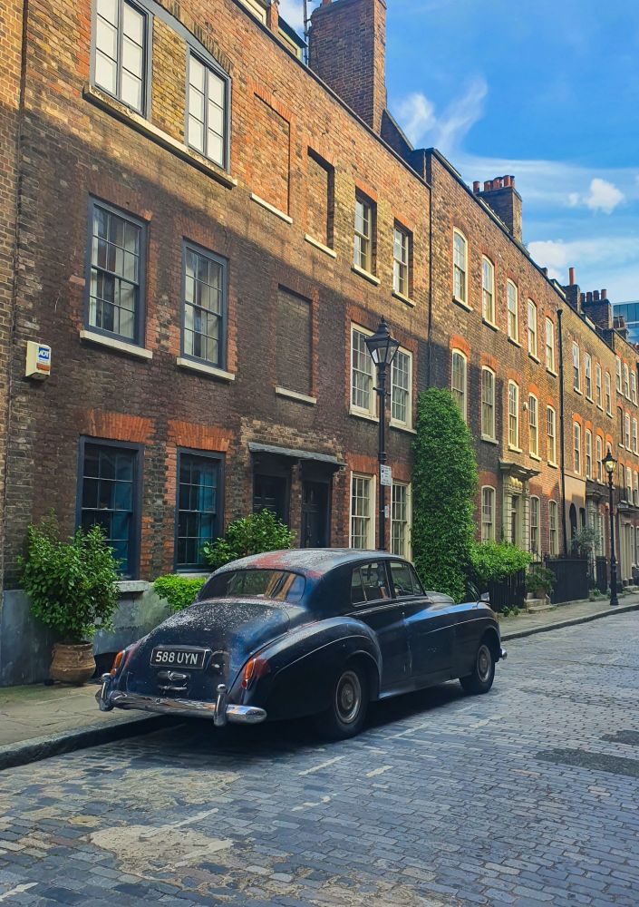a british old car in a bricky british street