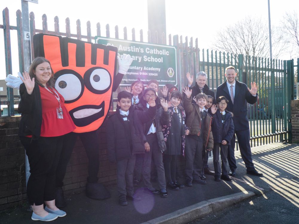 Simon Lightwood MP (standing on the far right) with staff and pupils from St Austin's Primary School and Living Streets' mascot Strider. They are standing outside the school gates.