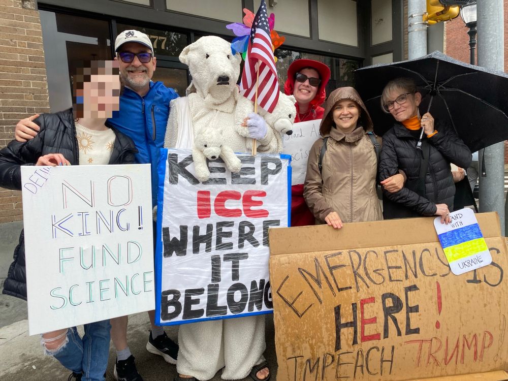 Brandeis faculty and staff at the Waltham No Kings demonstration, holding signs reading: "No King! Fund Science", "Keep ICE where it belongs" (held by Sabine von Mering dressed as a polar bear), "Emergency is here! Impeach Trump", and "Stand with Ukraine".