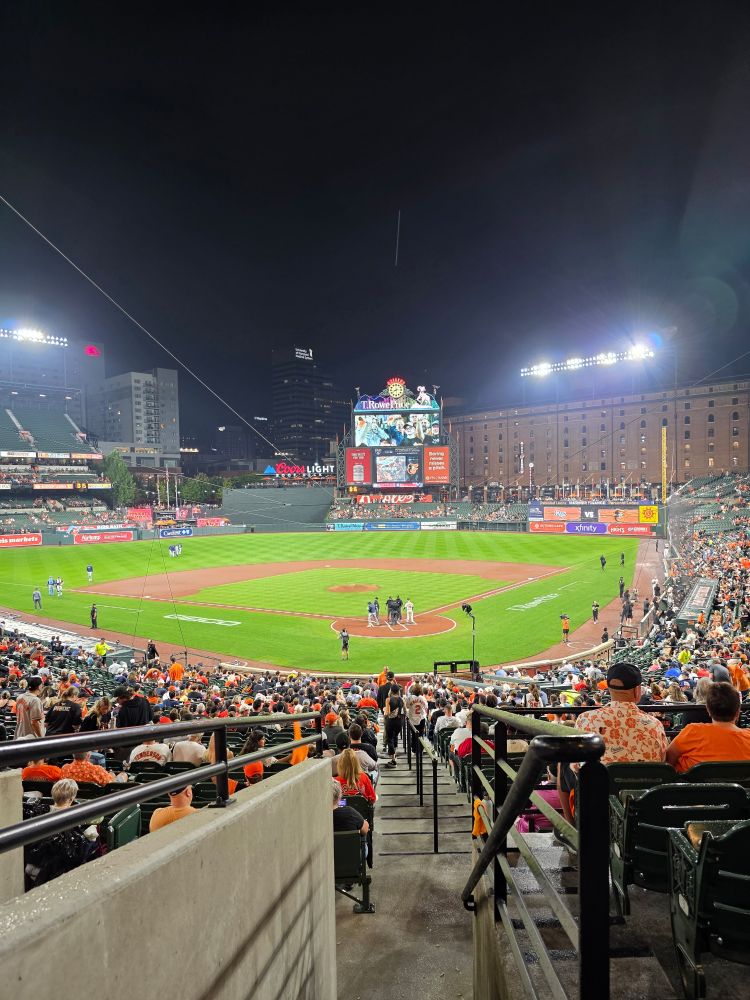 View from a seat at Camden Yards. Baseball field, scoreboard, warehouse. 