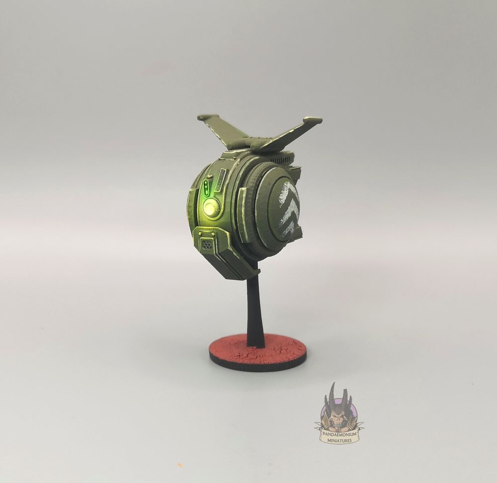 Drone - it's spherical with stablising fins at the top, in a drab green with grey chevron patterns on the side panels - front right view