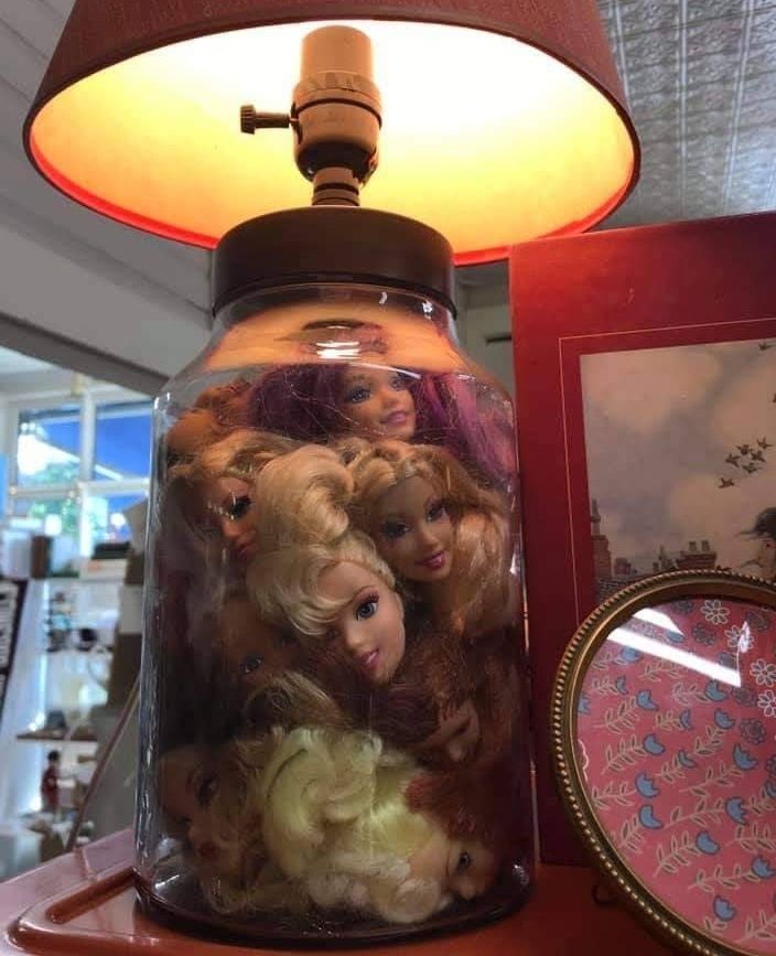 A thrift store lamp of questionable taste features several Barbie doll heads inside a transparent base.