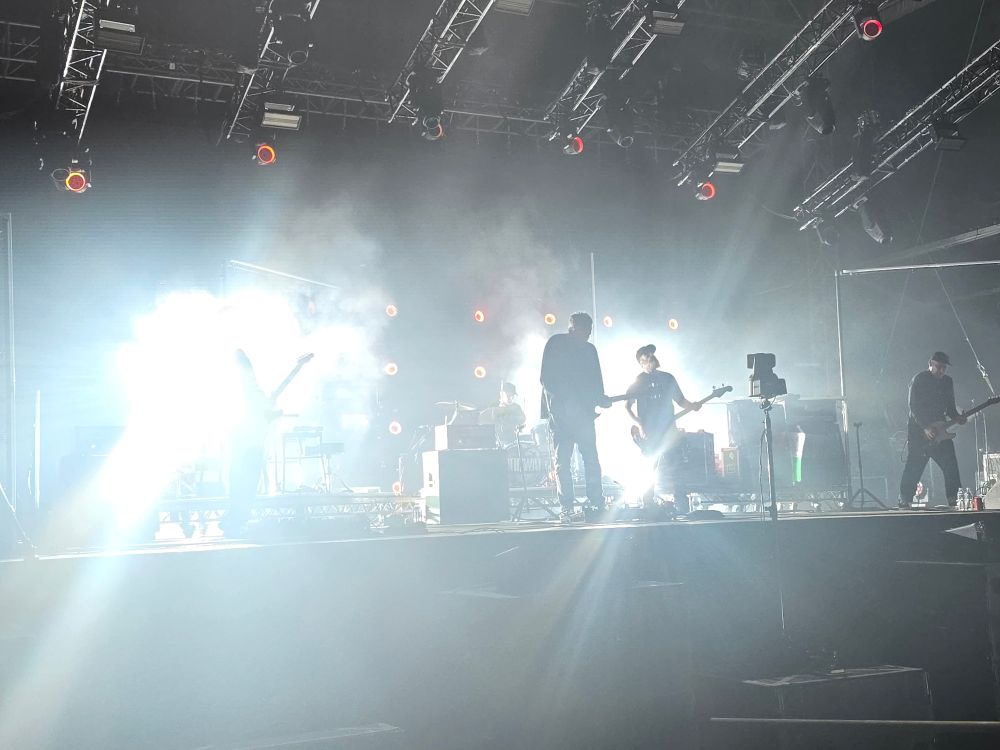 Bright lights on a stage, some vague figures with instruments are visible. 