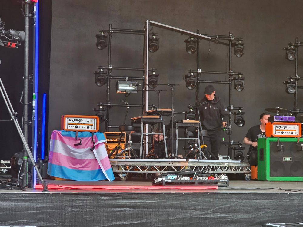 A trans pride flag on an amp on stage. 