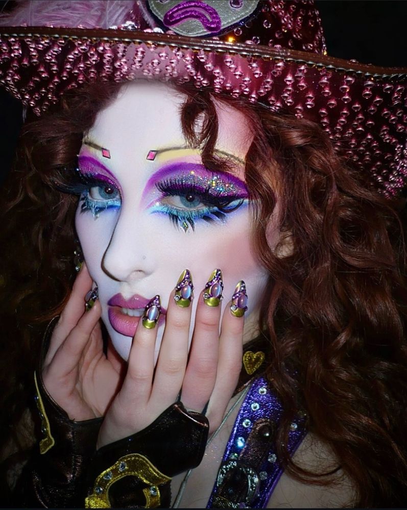 Close up of Chappell Roanms face highlighting make up and nails done in purples blues greens and pinks 