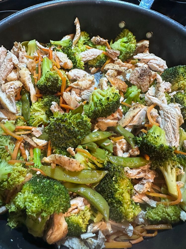 Picture of chicken stir fry with broccoli, shredded carrots, chicken thighs, snow peas, and garlic