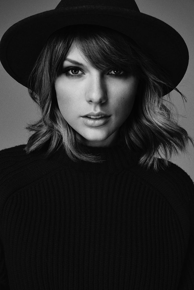A black and white close up of Taylor Swift in a black sweater and a bolero style hat