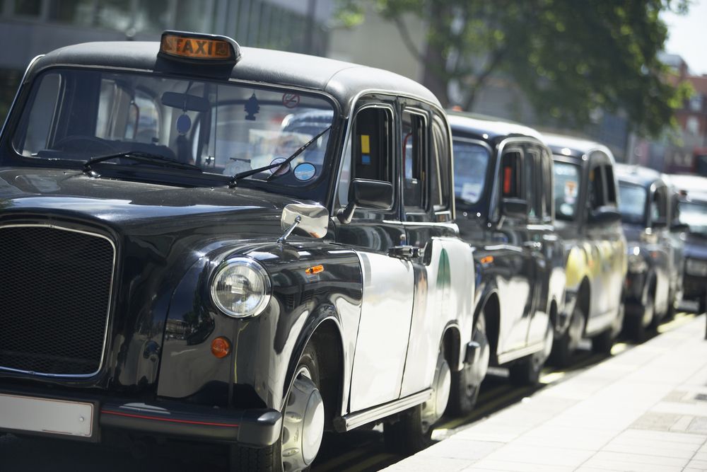 London taxis lined up on the sidewalk.