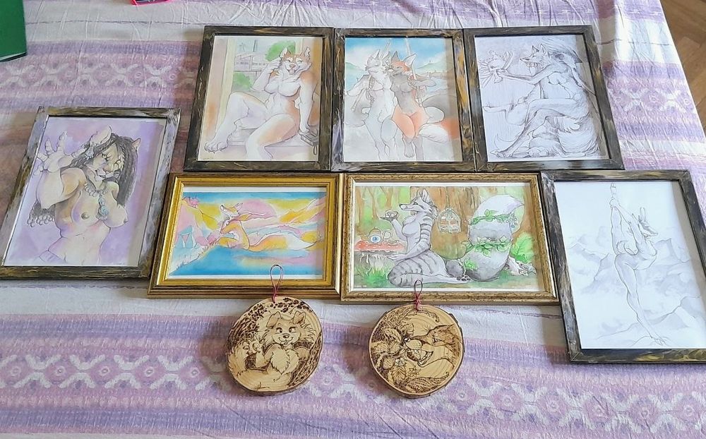Some framed pictures and two phyrograpies on a purple sheet 