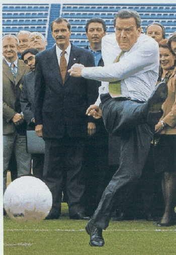 Foto eines Pressevents von der WM 2002 in Mexico.

Im Hintergrund stehen mehrere deligierte in Anzügen. In der Mitte des Bildes ist der Genosse der Bosse zu sehen wie er den mächtigen Tritt mit angespannter, aber heroischer Mine durchzieht. 