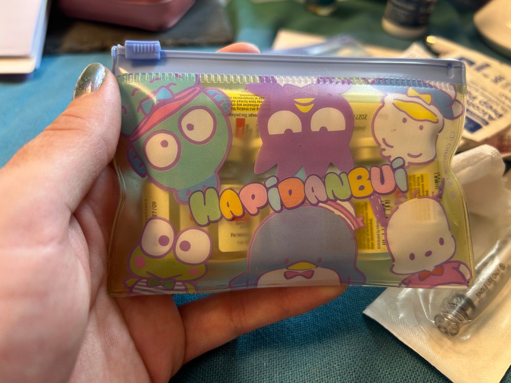 Me holding a small bag full of little testosterone bottles with the 6 cute boy Sanrio characters that make up their Hapidanbui group - Tuxedosam, Badtz-Maru, Hangyodon, Pochacco, Keroppi, and Pekkle.