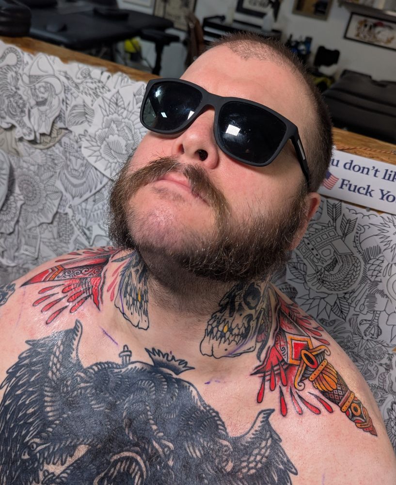 The poster sporting shades and some sweet fresh ink of a dagger going through his neck.