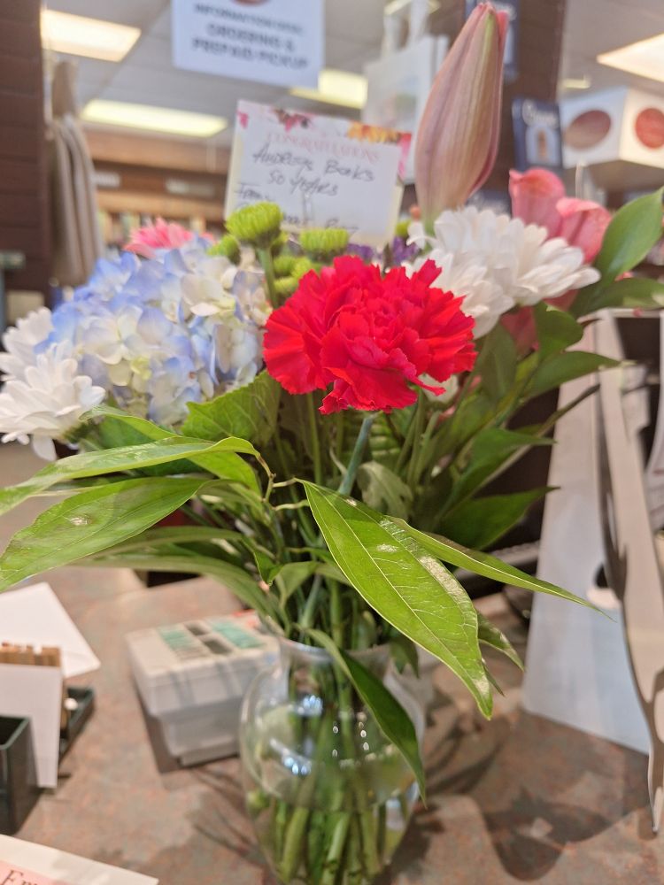 A vase of flowers on a store counter.