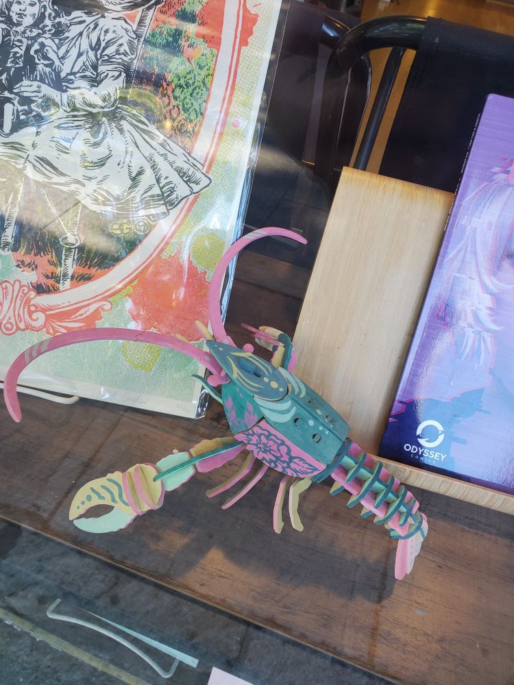 A wooden lobster painted in teal, pink, and yellow, in the front window.