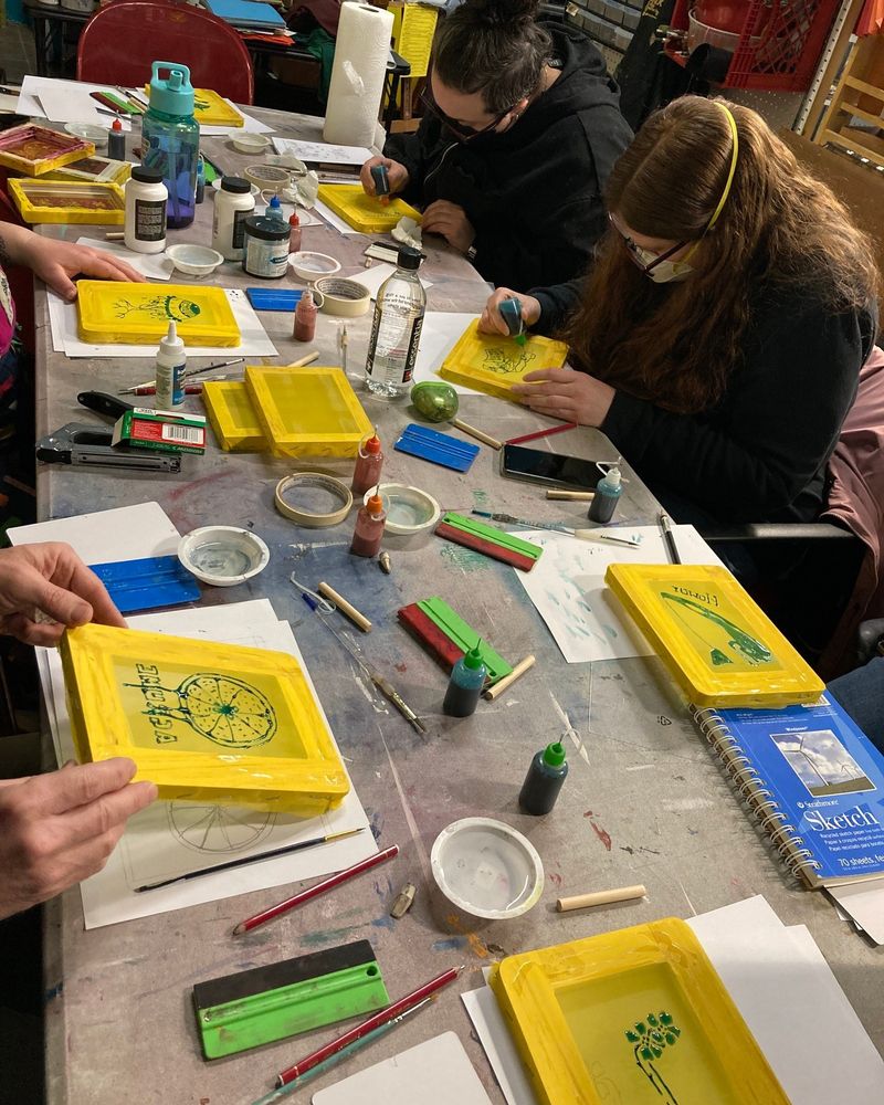 Photo of people working with small 4x6 screen printing frames at a table.