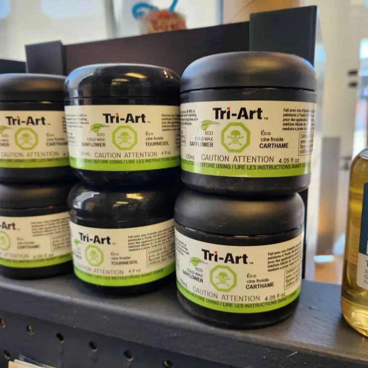 Various containers of Tri-Art eco cold wax stacked on a shelf.
