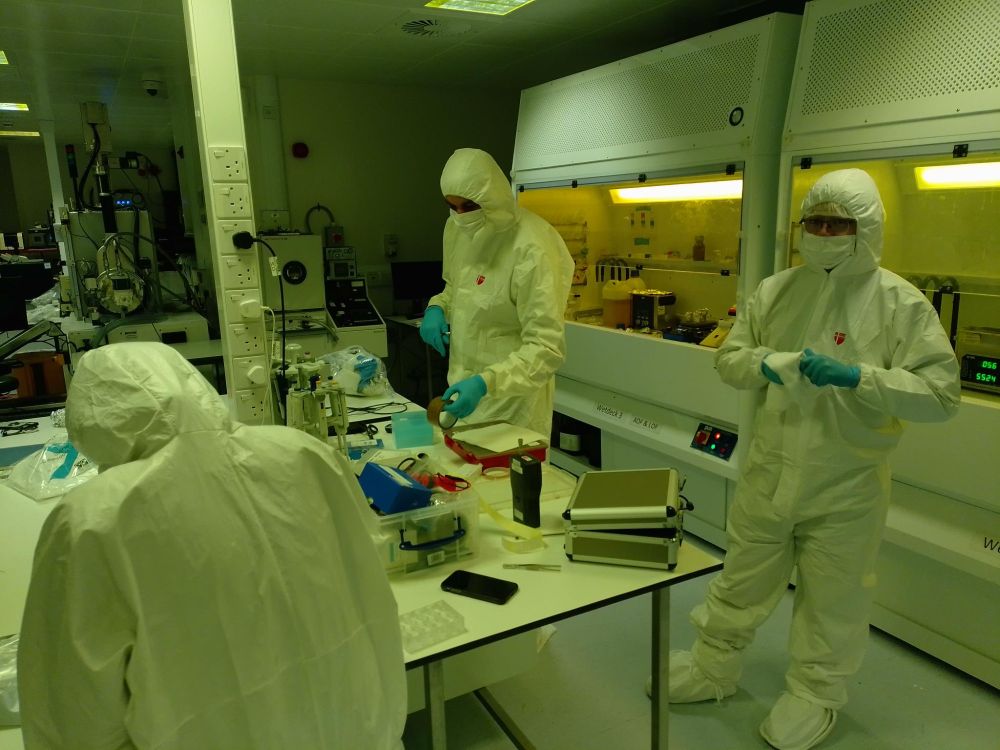 Cleanroom users dressed in their white PPE suits. Behind them are the fume hoods.