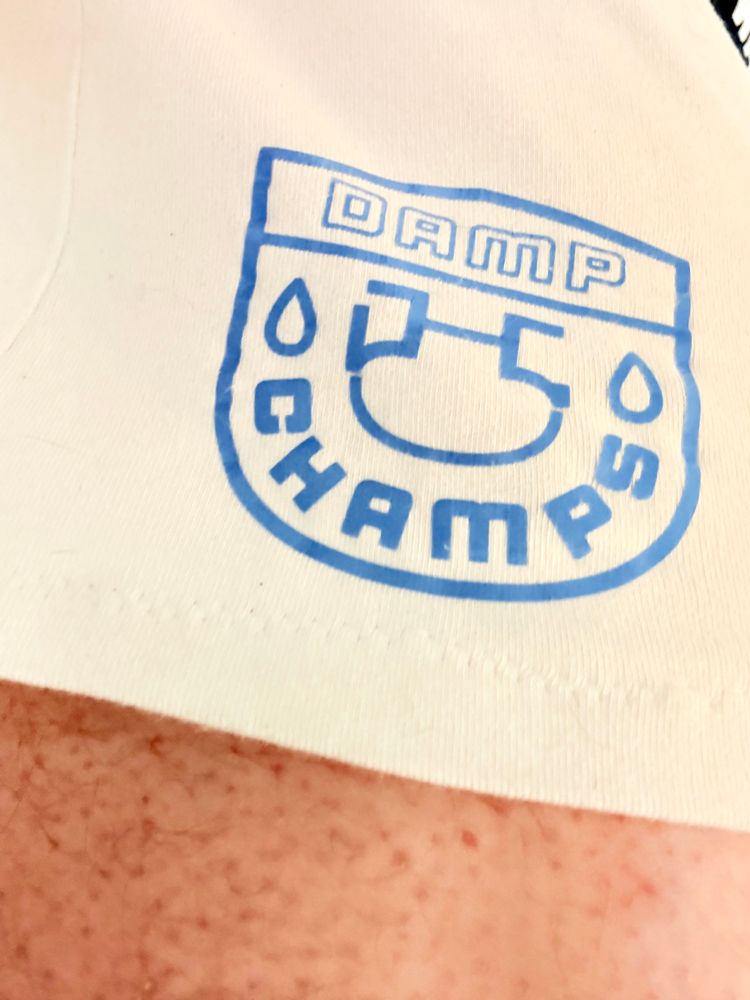 A closeup photo of a pair of white football shorts. The shorts have a logo saying “damp champs”.
