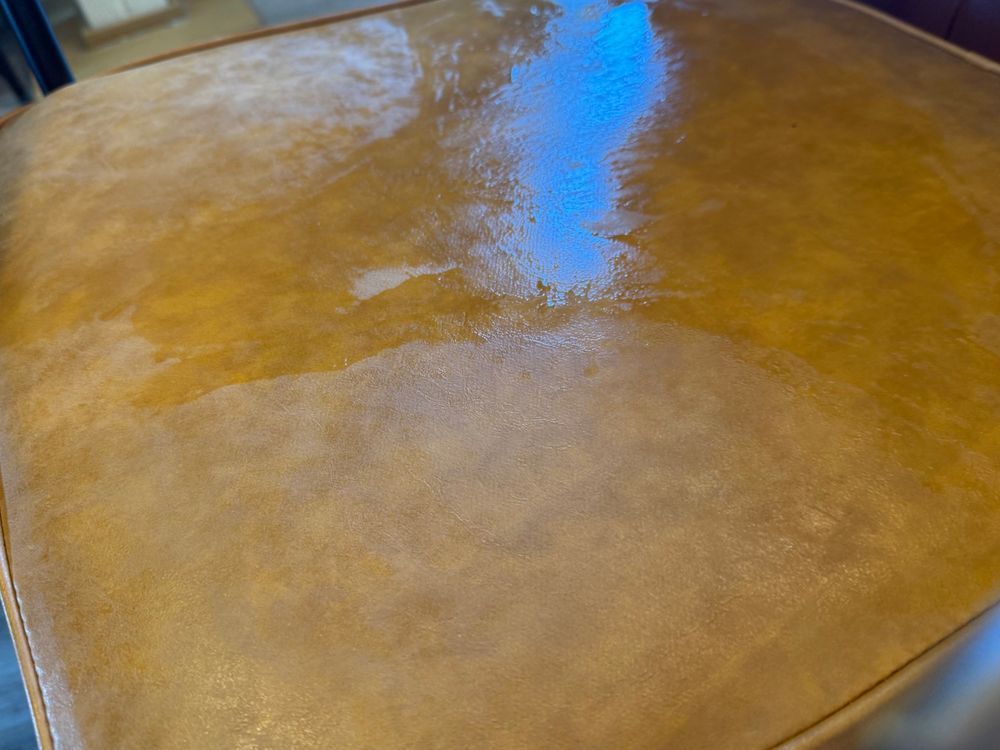 A photo of a large wet patch on a leather chair seat.